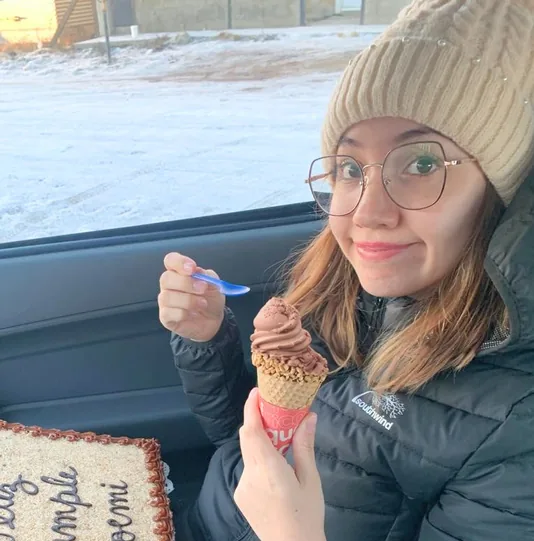 Erica in a knitted hat in the car, holding an ice cream