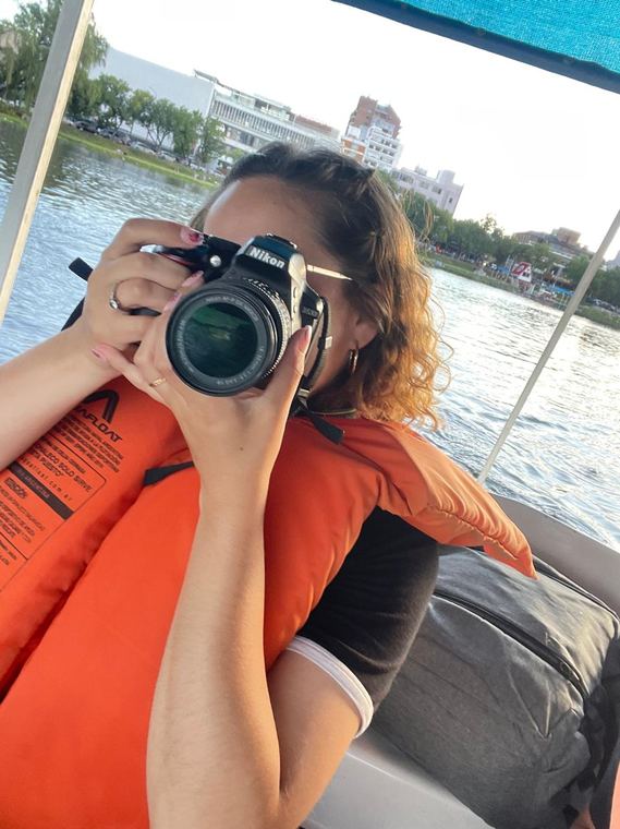 Erica shooting with a Nikon camera from a boat on the lake