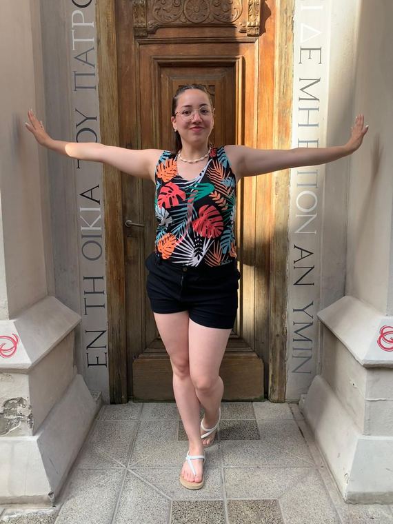 Erica standing with both arms out in a carved wooden doorway