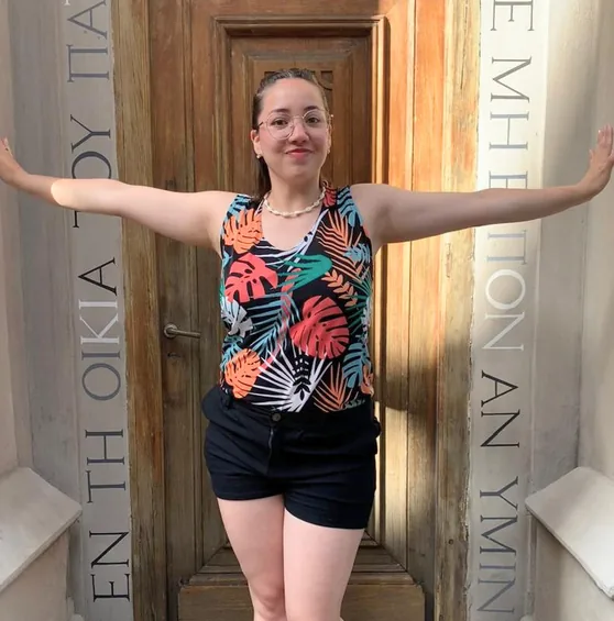 Erica standing with both arms out in a carved wooden doorway