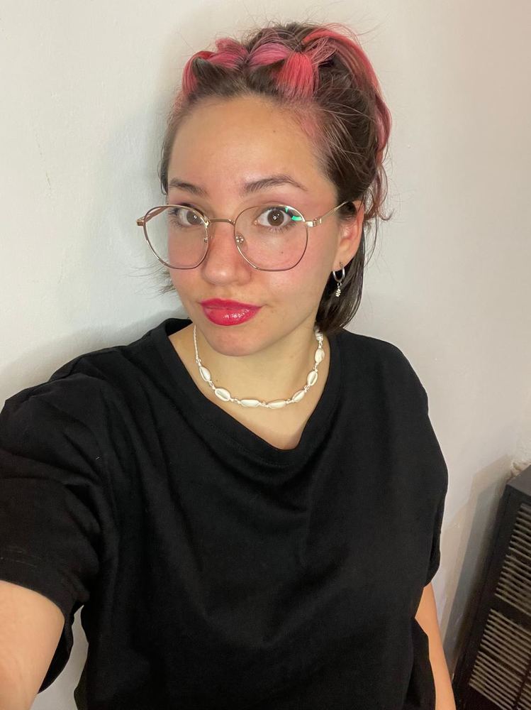 Erica in a black tee, hair braided through with pink, looking straight at the camera