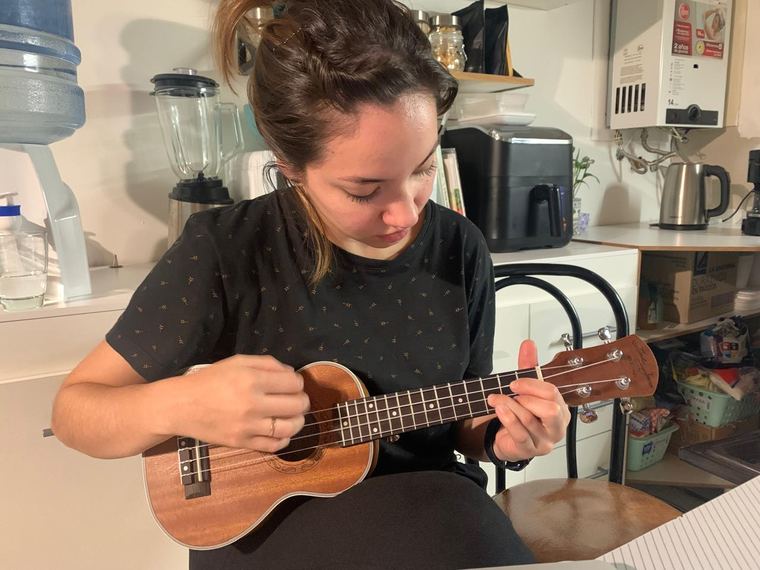 Erica playing a ukulele at the kitchen counter